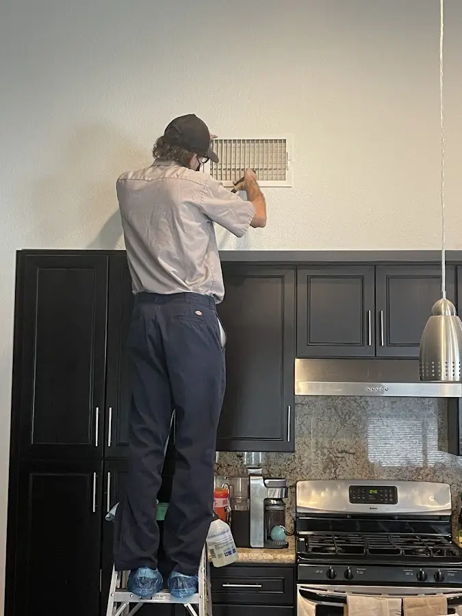 Technician inspecting an air vent during HVAC service in Bowleys Quarters